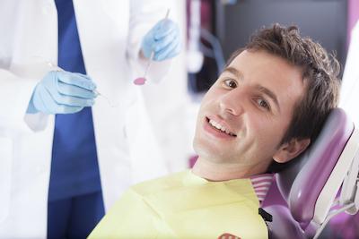 man smiling in dentist exam chair | dentist medina oh