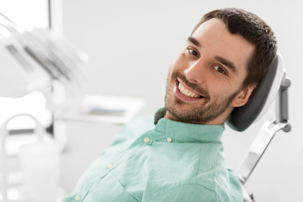 man smiling in dentist exam chair | dental implants akron