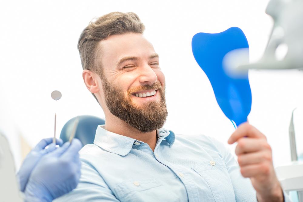 man smiling with mirror | second opinion dentist