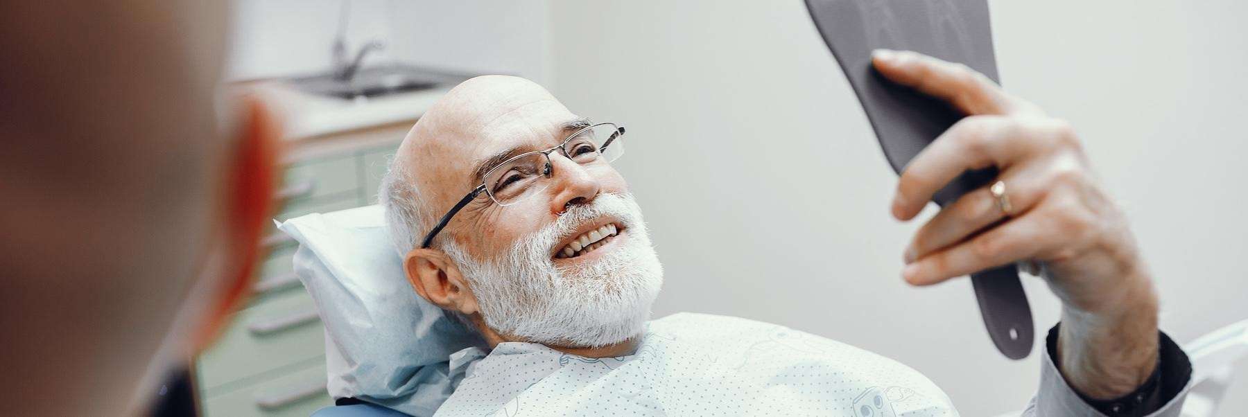 man looking at mirror in chair | best prosthodontics in medina